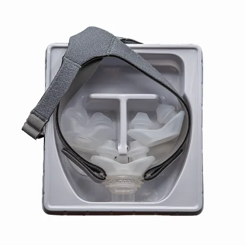 The Opti+ MiniPAP nasal-pillow CPAP mask with headgear, shown in its packaging tray (top view)