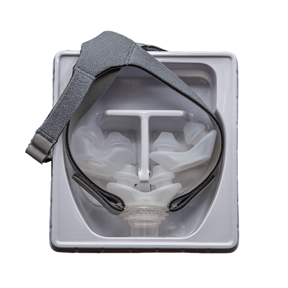 The Opti+ MiniPAP nasal-pillow CPAP mask with headgear, shown in its packaging tray (top view)