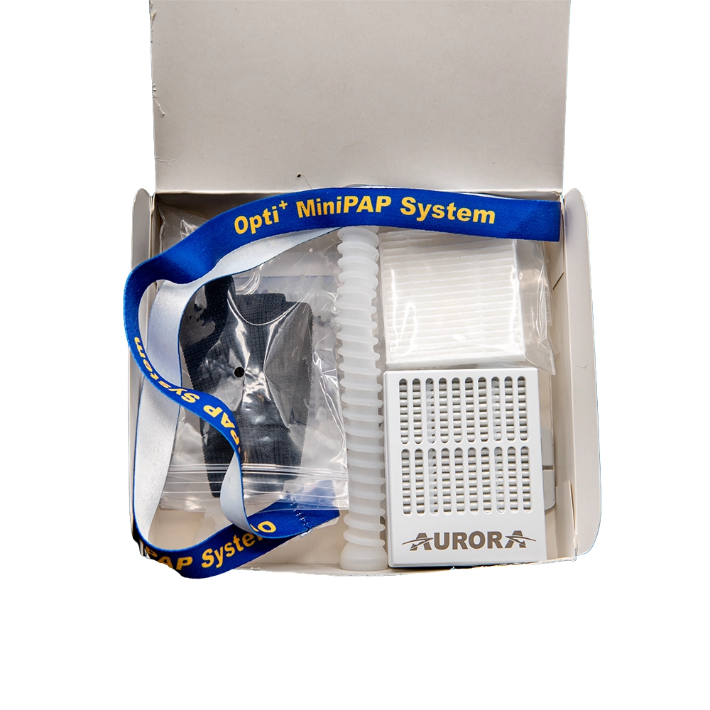 The complete Opti+ MiniPAP System kit in its box — nasal-pillow mask, headgear, hose, and the AURORA battery-powered air blower