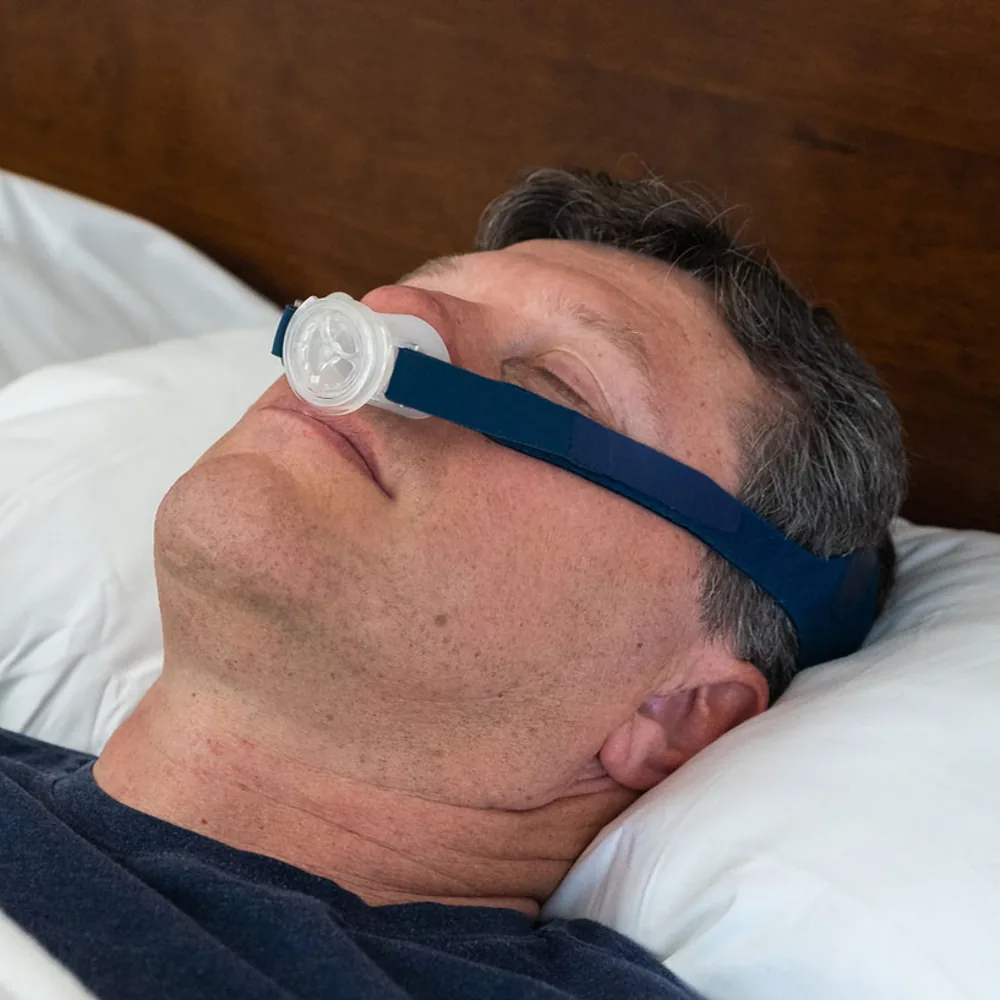 A man asleep on his back wearing the OptiPillows EPAP mask