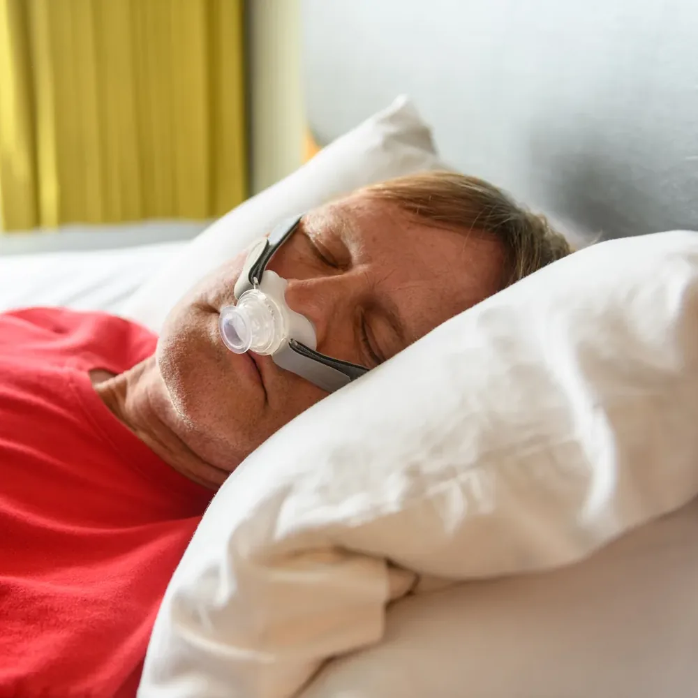A man asleep on his side wearing the OptiPillows EPAP mask